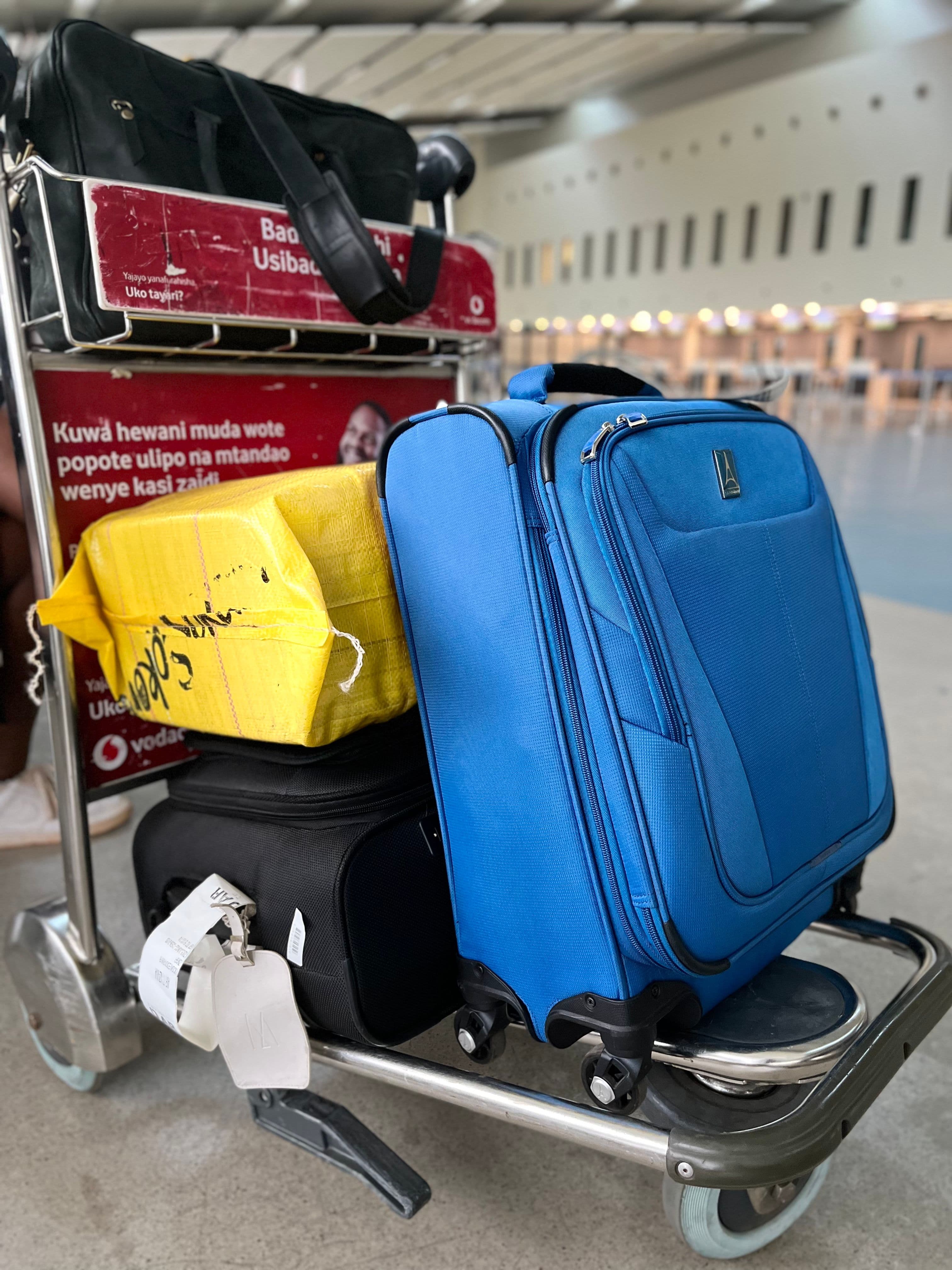 A luggage trolley loaded with suitcases at an airport terminal, evoking the trip-planning season around travel fairs.