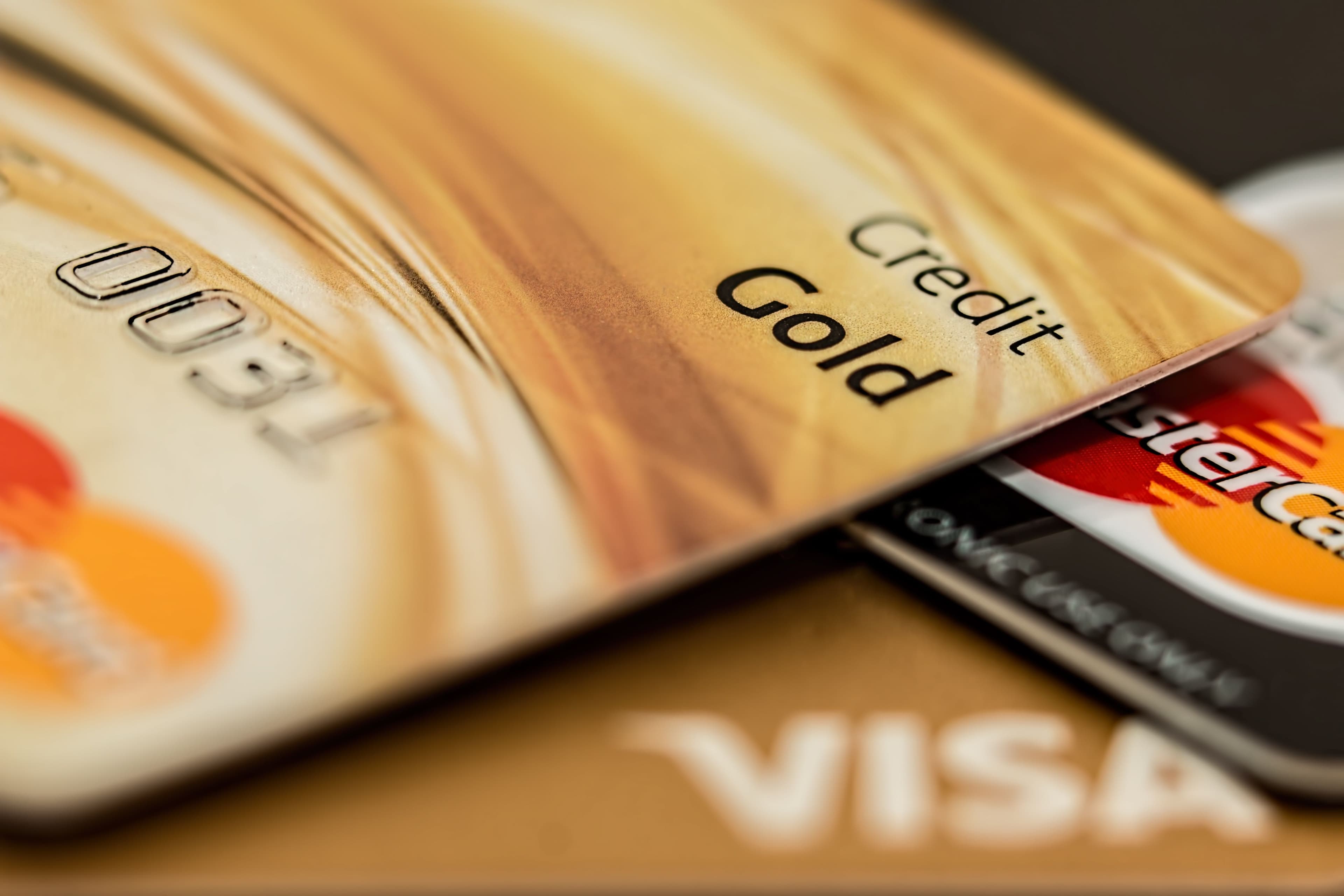 A close-up stack of assorted branded credit cards with a gold card in sharp focus against a blurred background.