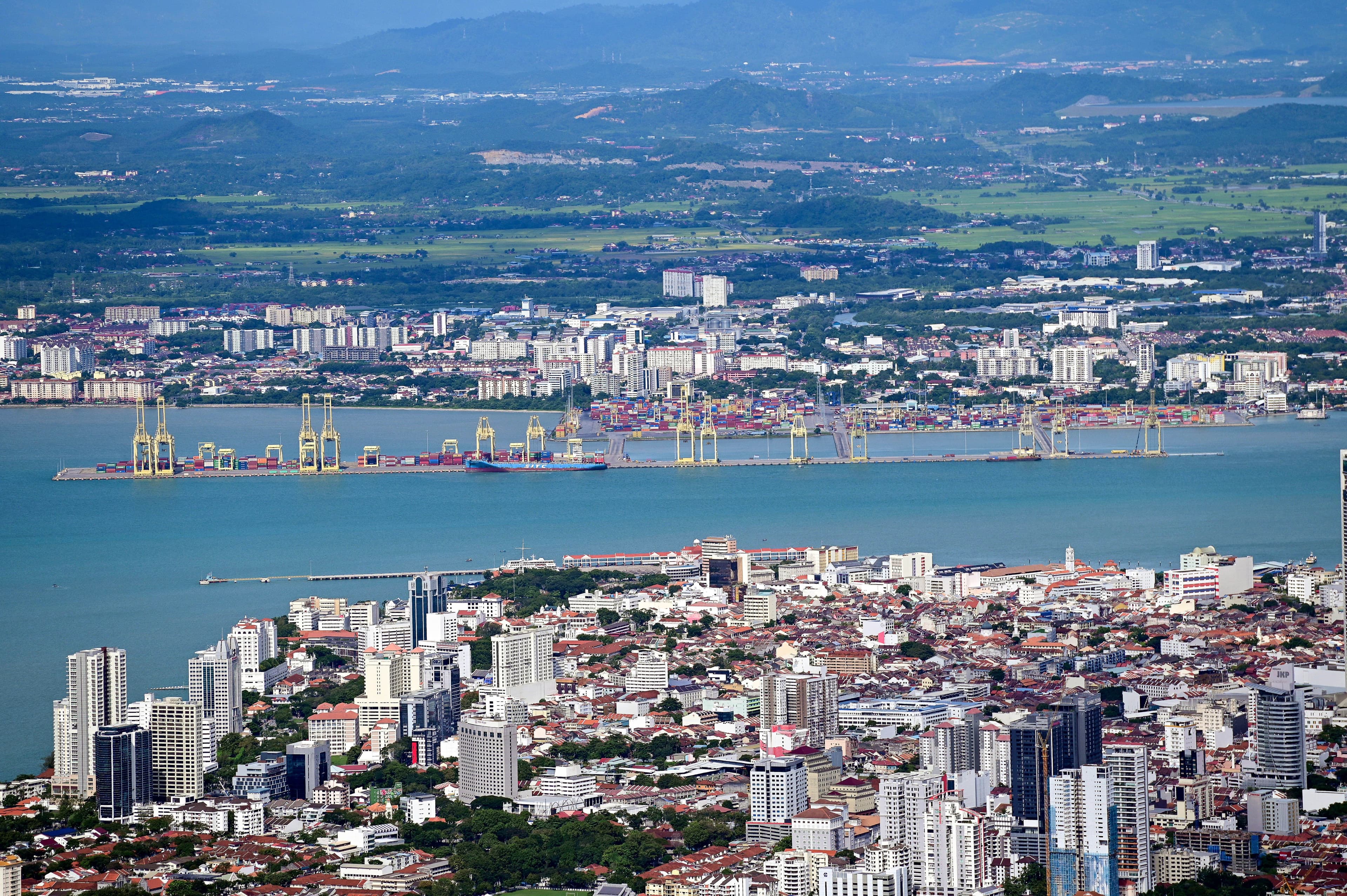 Aerial daytime view of George Town's waterfront cityscape and cargo port in Penang, Malaysia.