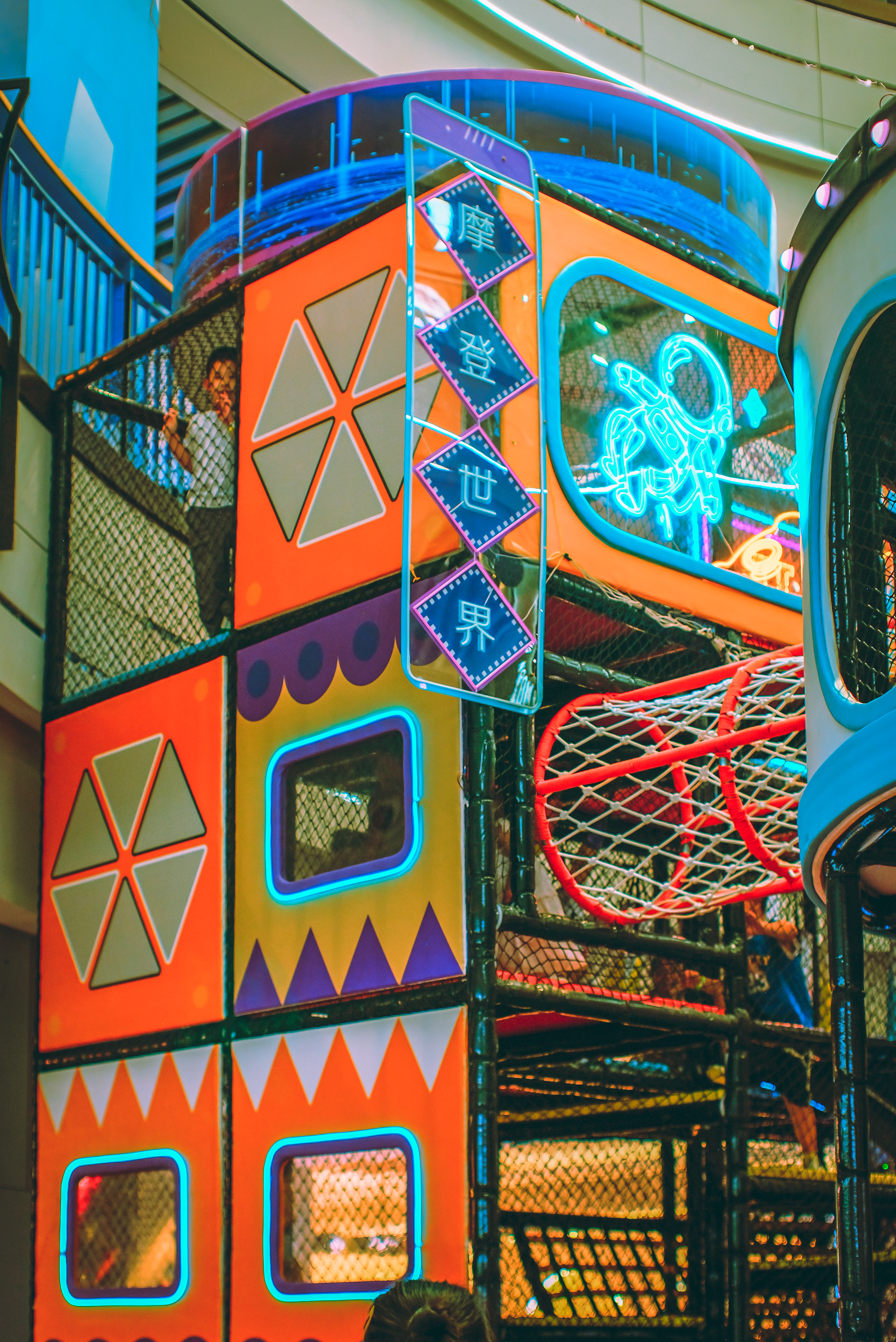 A colourful indoor playground with neon lighting and geometric play structures.
