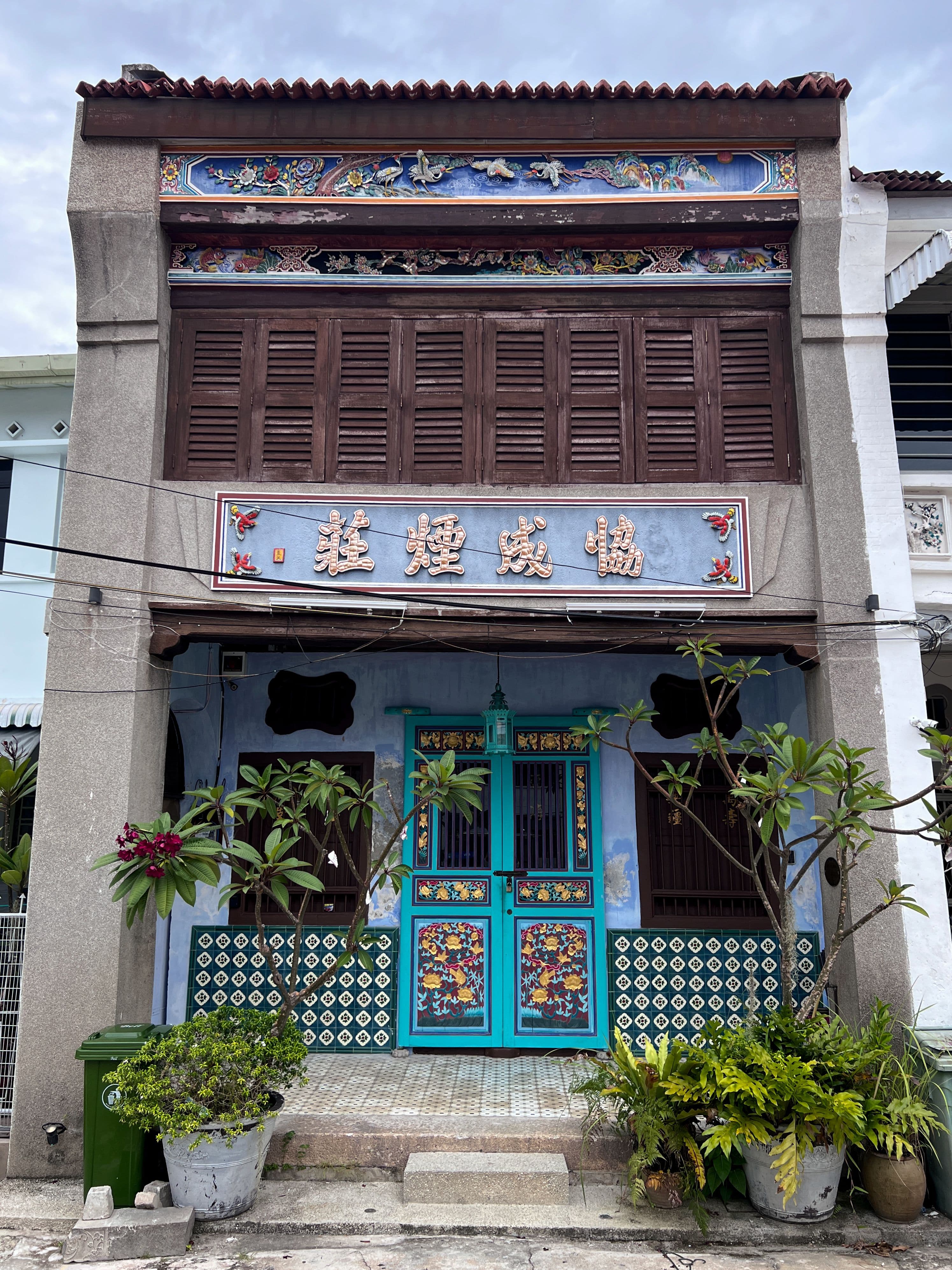 A colourful Peranakan shophouse facade in George Town, Penang, decorated with ornate tiles and Chinese signage.