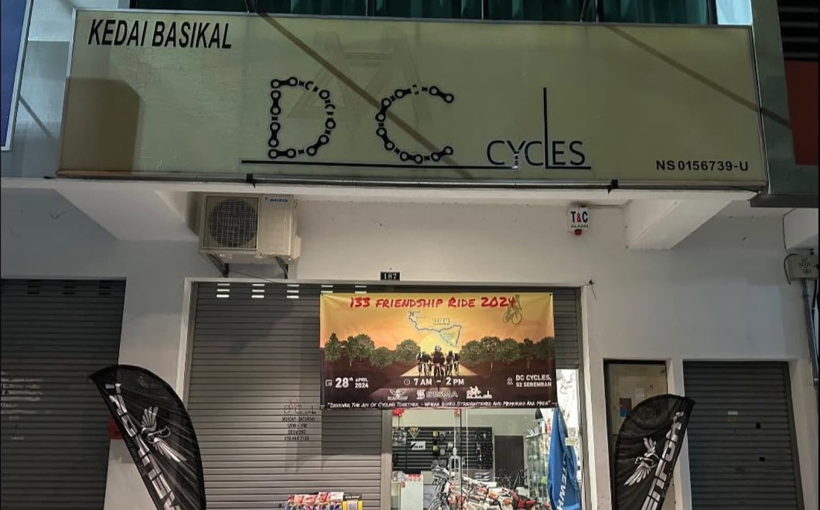 The DC Cycles shopfront in Seremban 2 at night, its Kedai Basikal sign lit above a Friendship Ride banner