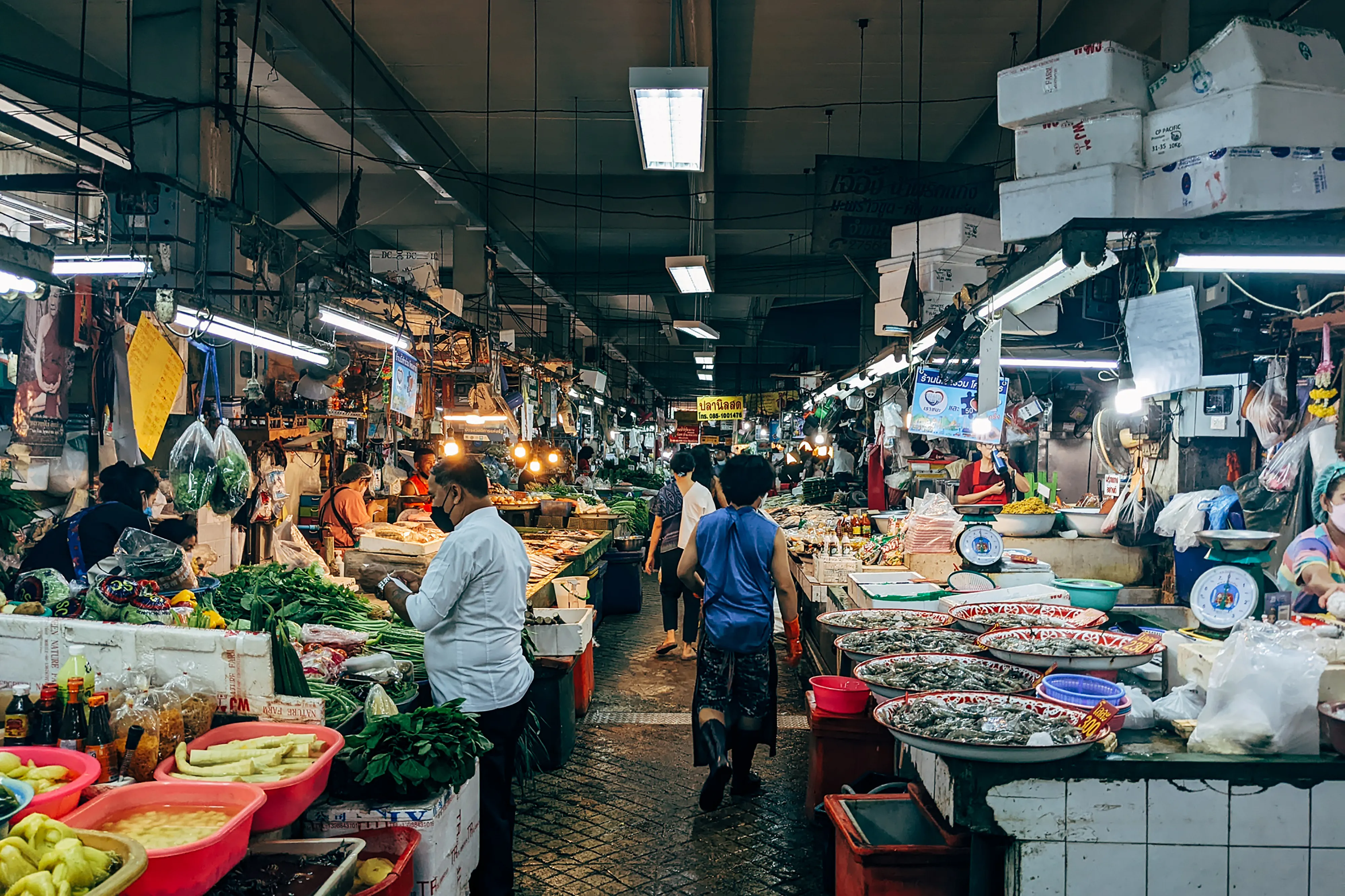 Shoppers browse fresh produce stalls inside a busy indoor wet market.