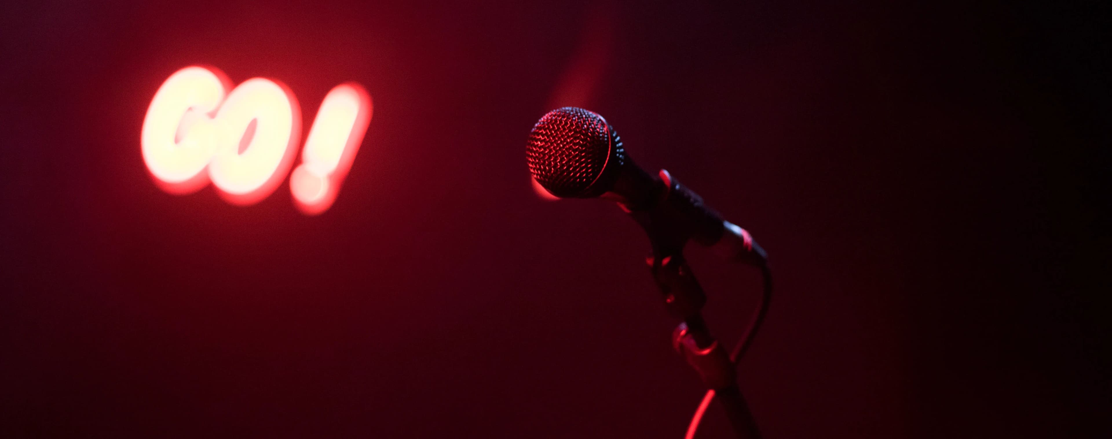 A microphone on a stage under a glowing red sign.