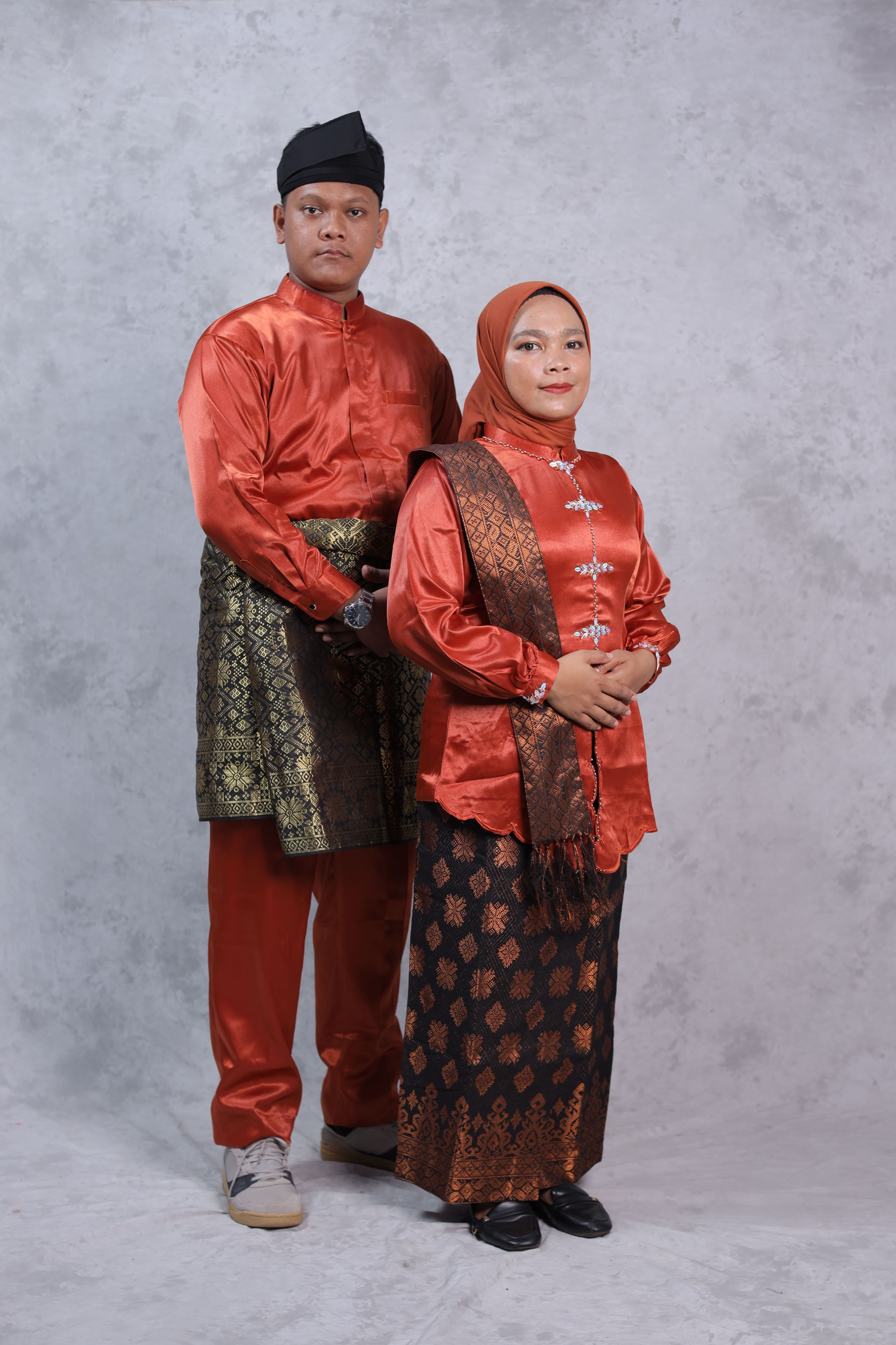 A couple photographed in traditional Malay ceremonial dress, the style of clothing historically paired with handwoven songket fabric.