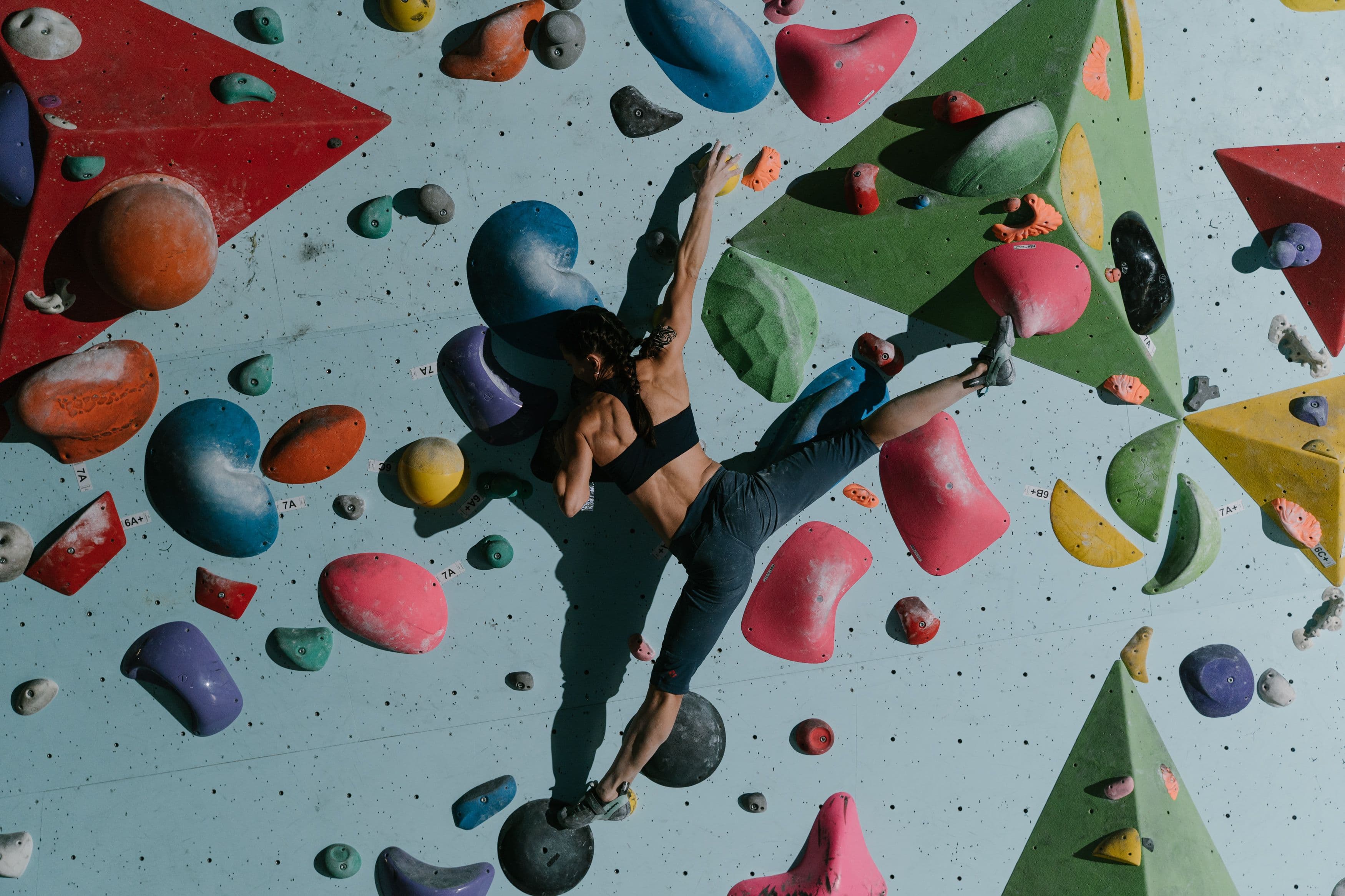 A climber reaches for a colourful hold on an indoor bouldering wall, in a generic stock photo of a climbing gym rather than a specific Klang Valley venue.