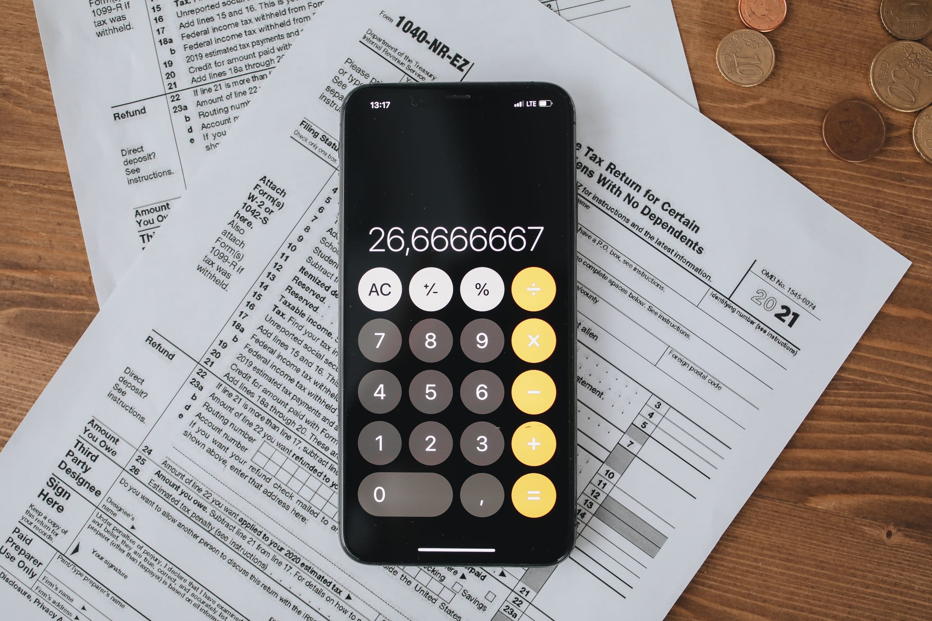 A calculator resting on tax paperwork on a wooden desk, representing income tax filing and refund calculations.
