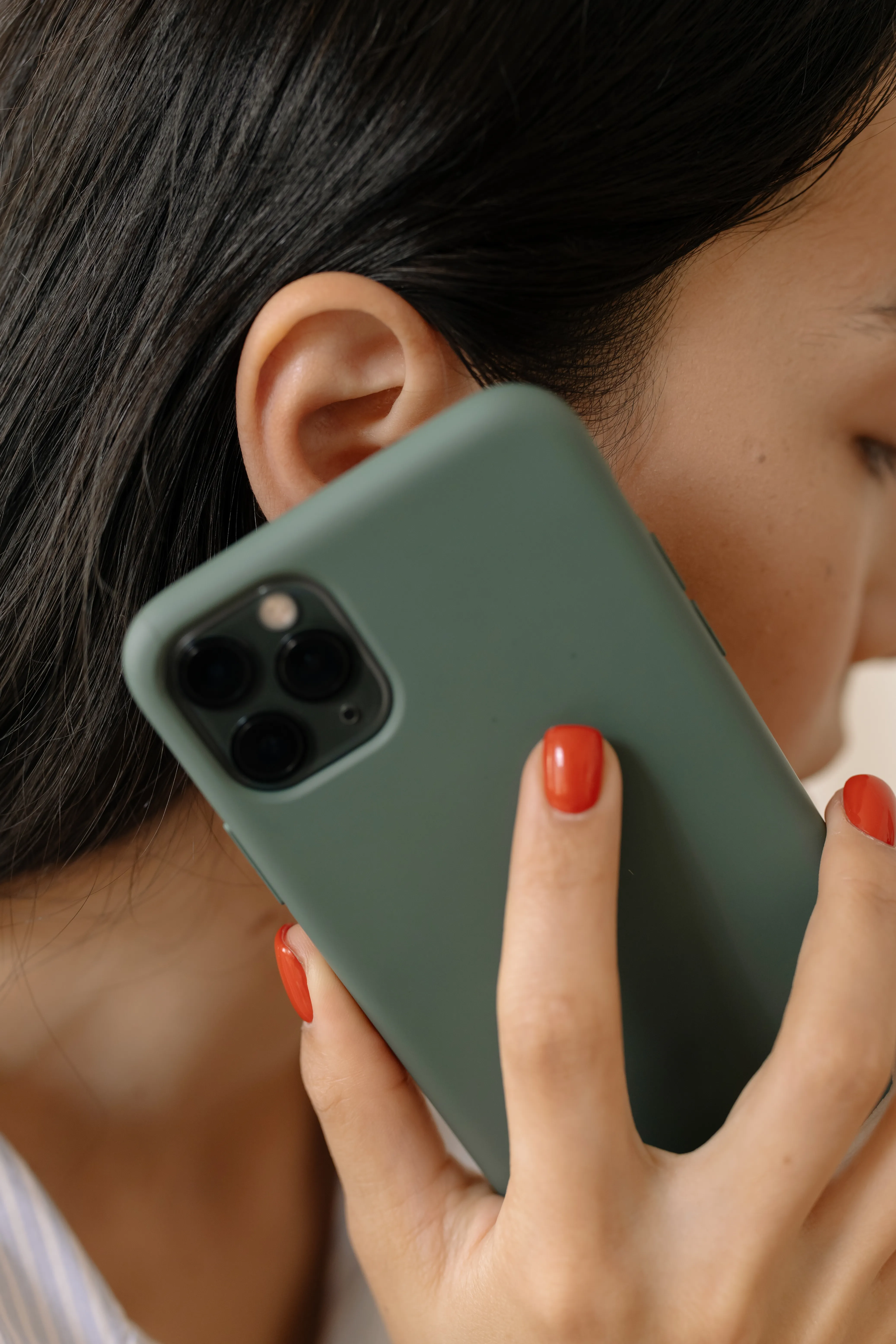 A woman holding a smartphone to her ear in close-up.