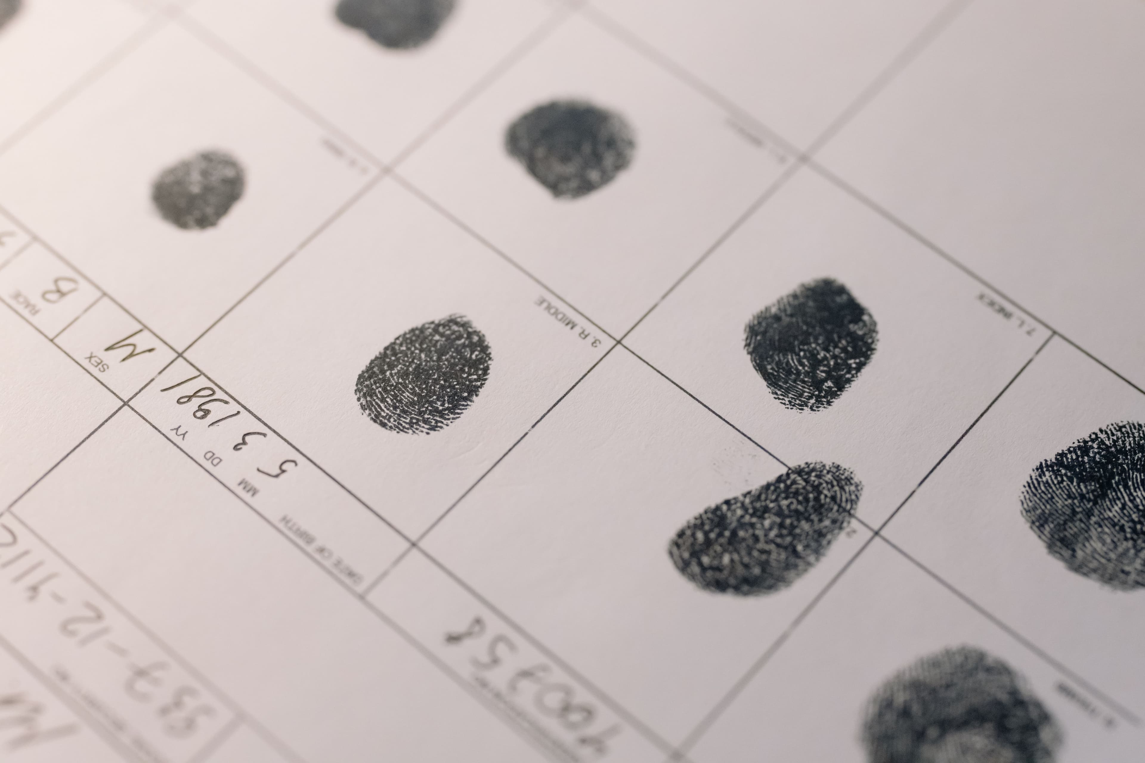 Close-up of ink fingerprints being pressed onto an official document, illustrating the biometric identity verification process.