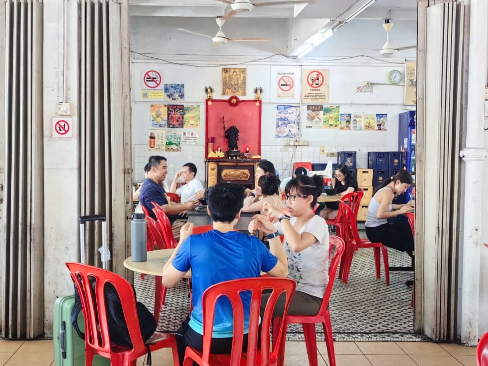 The Sea Park kopitiam interior, with red plastic chairs and customers eating at round tables